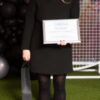 Woman in all black stands with awards certificate.