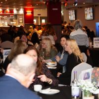 A busy hall filled with tables of people at awards ceremony. 