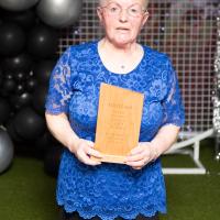 Woman in blue top smiles with award. Muriel Fleming, Chatty Crafters. 