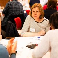 Group of people in mid discussion around a table. 