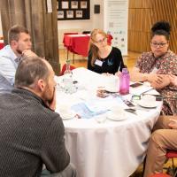 Group of people in mid discussion around a table. 