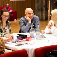 Group of people in mid discussion around a table. 