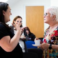 Two women laugh as they are seen talking at the event. 