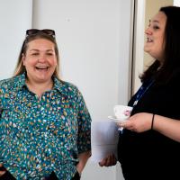 Two women laugh as they are seen talking at the event. 