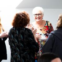 Group of people in mid discussion standing in a white room. 