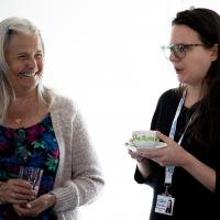 Two women laugh as they are seen talking at the event. 