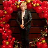 One woman poses in front of red balloon display. 
