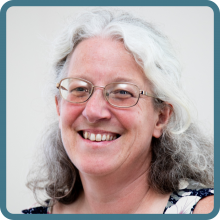 Woman with glasses smiles at camera, 
