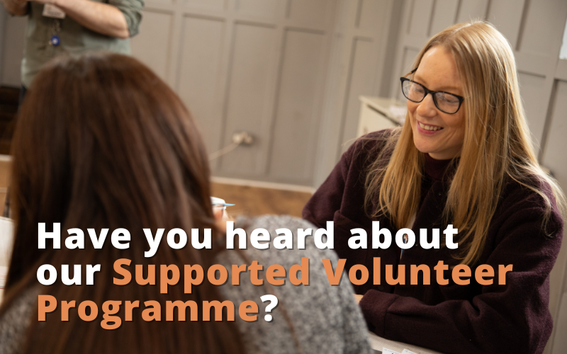 Two women sit laughing. Text reads "Have you heard about our Supported Volunteer Programme?"